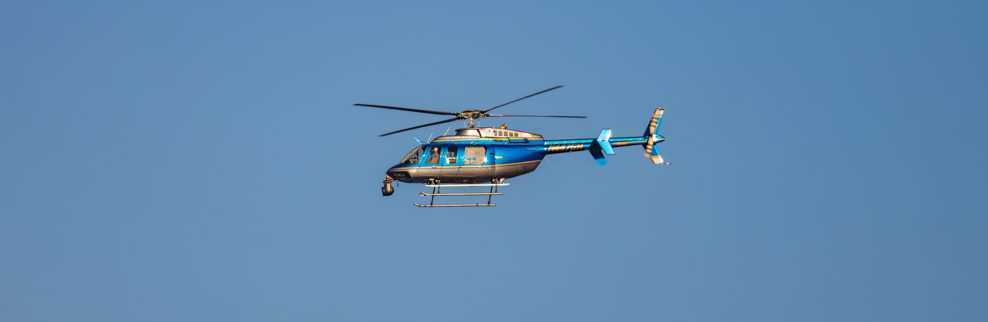 A blue helicopter in flight against a clear blue sky, showcasing smooth aerial maneuvering.