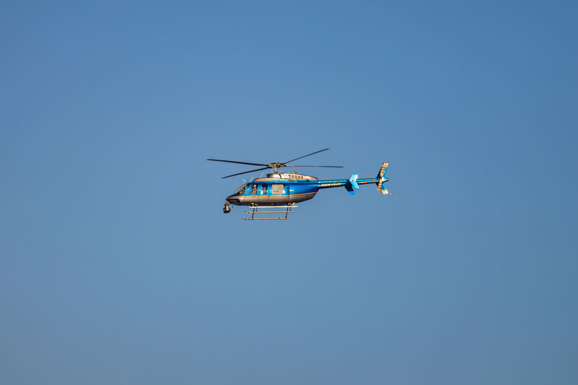 A blue helicopter in flight against a clear blue sky, showcasing smooth aerial maneuvering.