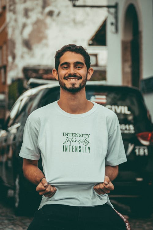 Man in White T-shirt Standing Near a Car