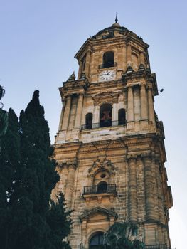 Majestic view of the Málaga Cathedral clock tower against a clear blue sky, Spain.