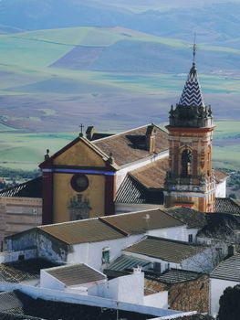 Aerial photograph of a picturesque church in a historic Spanish town beside green fields.