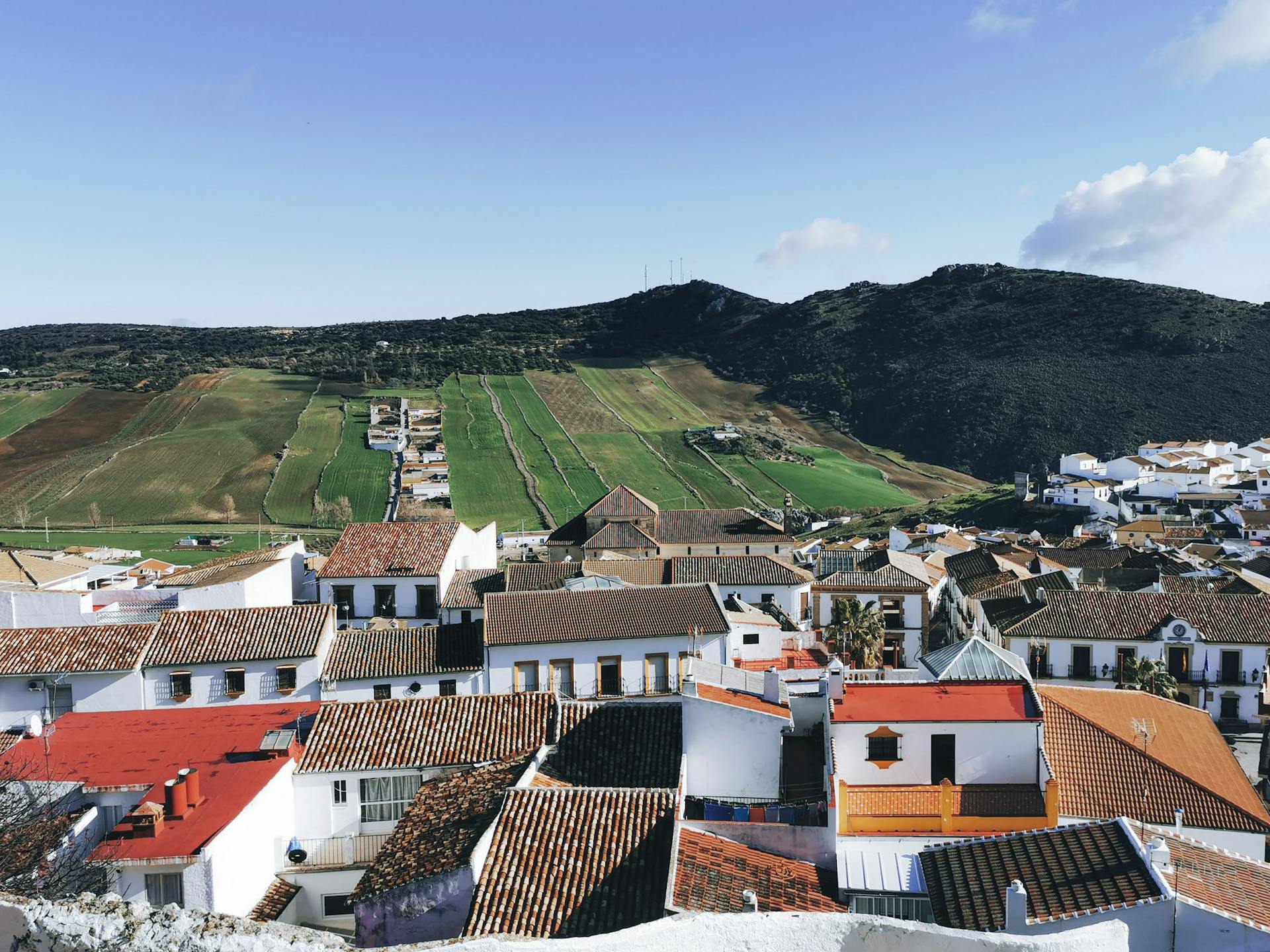 White and Brown Concrete Houses Near Green Mountain Under Blue Sky