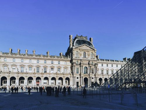 Free The historic Louvre Museum facade in Paris attracts visitors for sightseeing. Stock Photo