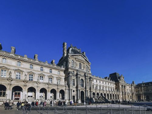 Free Beautiful architectural view of the Louvre Museum facade under a clear blue sky in Paris, France. Stock Photo