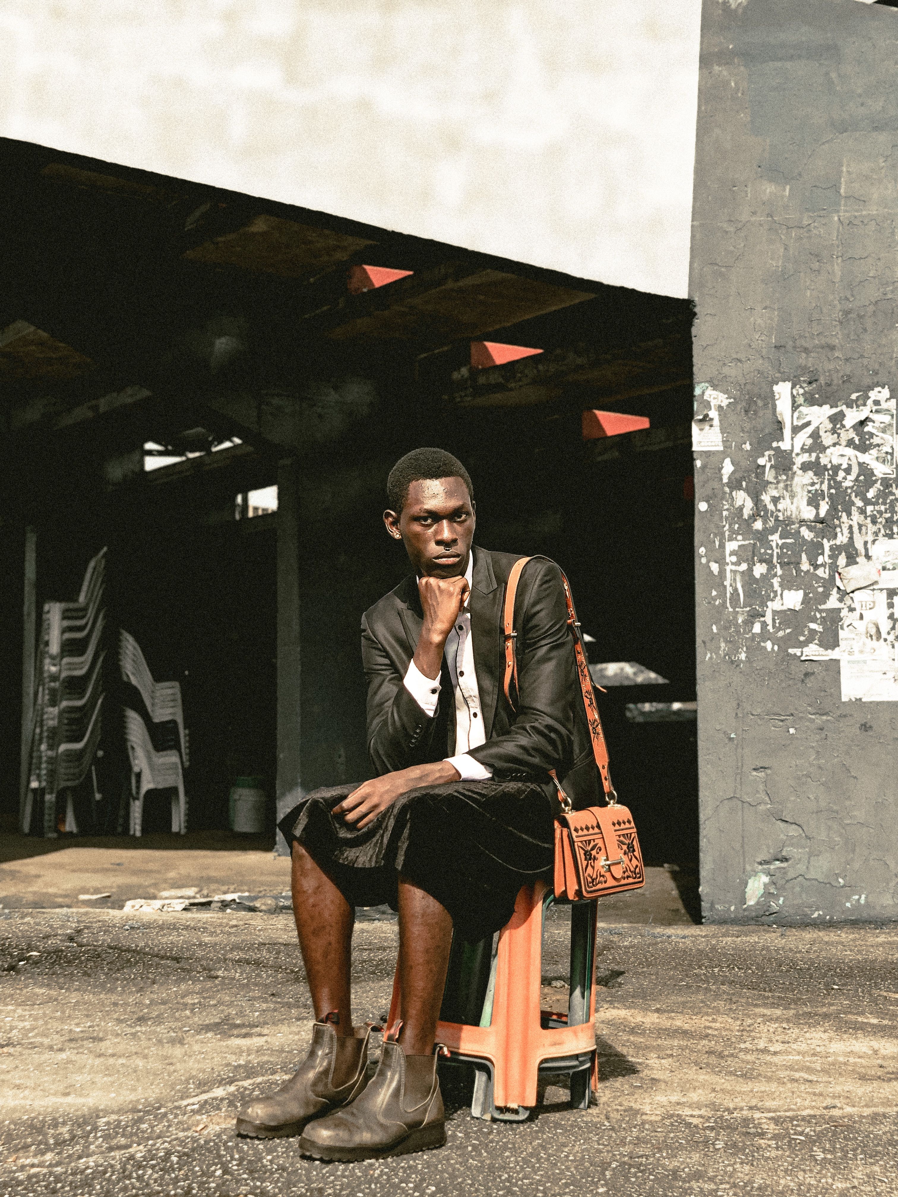 A thoughtful man in a suit poses stylishly in an urban environment with unique lighting.