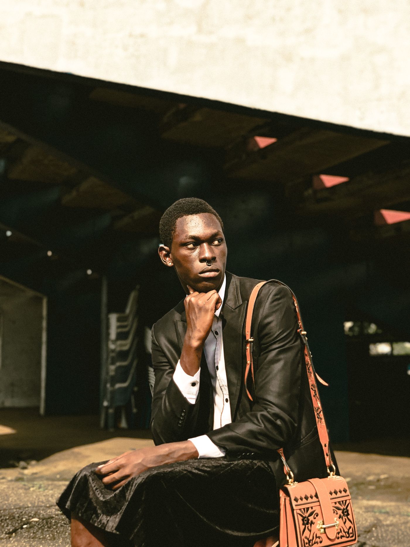 Editorial portrait of a man in a dark tailored suit against a softly blurred urban backdrop