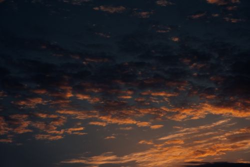Free A stunning view of sunset clouds with orange and gold hues creating a dramatic sky scene. Stock Photo