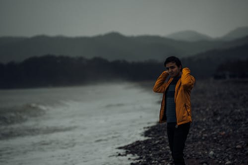 A Man in Yellow Jacket Standing on the Beach
