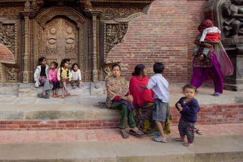 Free Group of Nepalese children sitting in front of an intricately carved palace entrance. Stock Photo