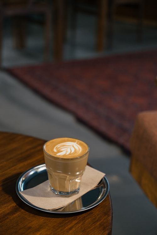 Free A cozy indoor cafe scene with a cappuccino featuring latte art on a wooden table. Stock Photo