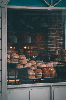 A warm display of freshly baked bread seen through a bakery's glass window.