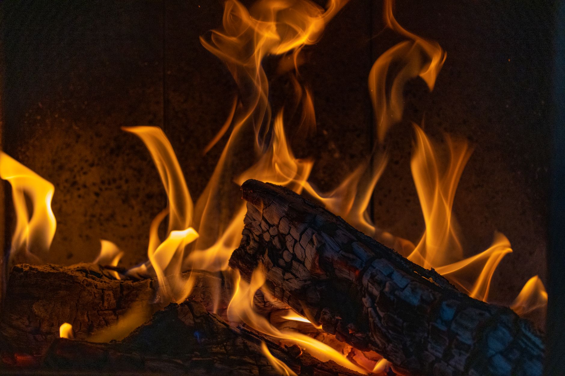 A close-up view of vibrant flames dancing around burning firewood creating a warm ambience.