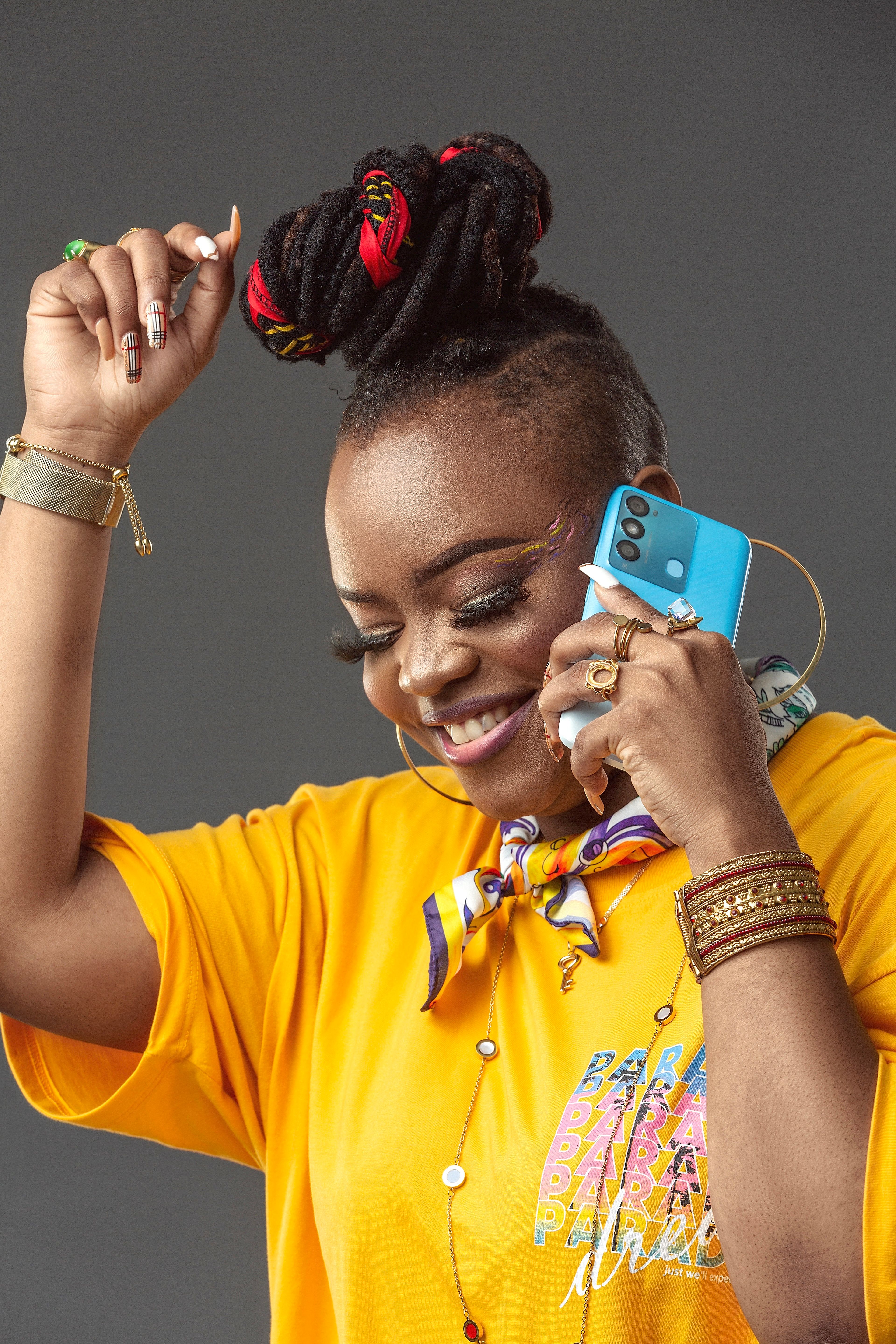 Smiling woman in yellow fashion with phone, showcasing lively style and energy.