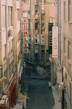 Moody narrow street with vintage building signs and graffiti in an urban setting.