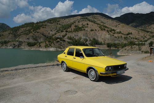 A Yellow Classic Car Parked Near the Lake and Mountain