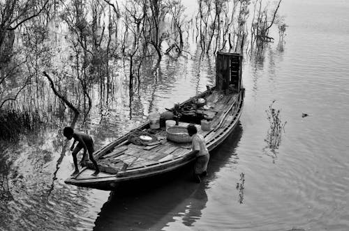 Free Grayscale Photography of Fishermen on a Wooden Boat Stock Photo