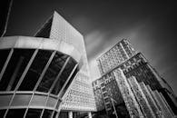 一张黑白照片，以戏剧性手法展现了具有几何图案和独特建筑的现代摩天大楼