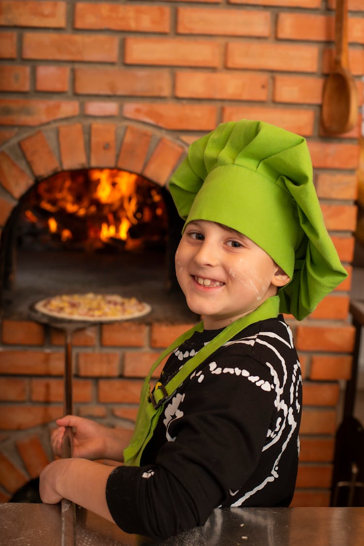 A Boy Cooking Pizza In A Brick Oven