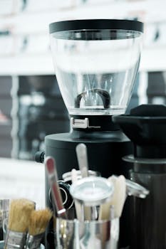 Close-up of an electric coffee grinder with kitchen utensils, showcasing modern kitchen equipment.