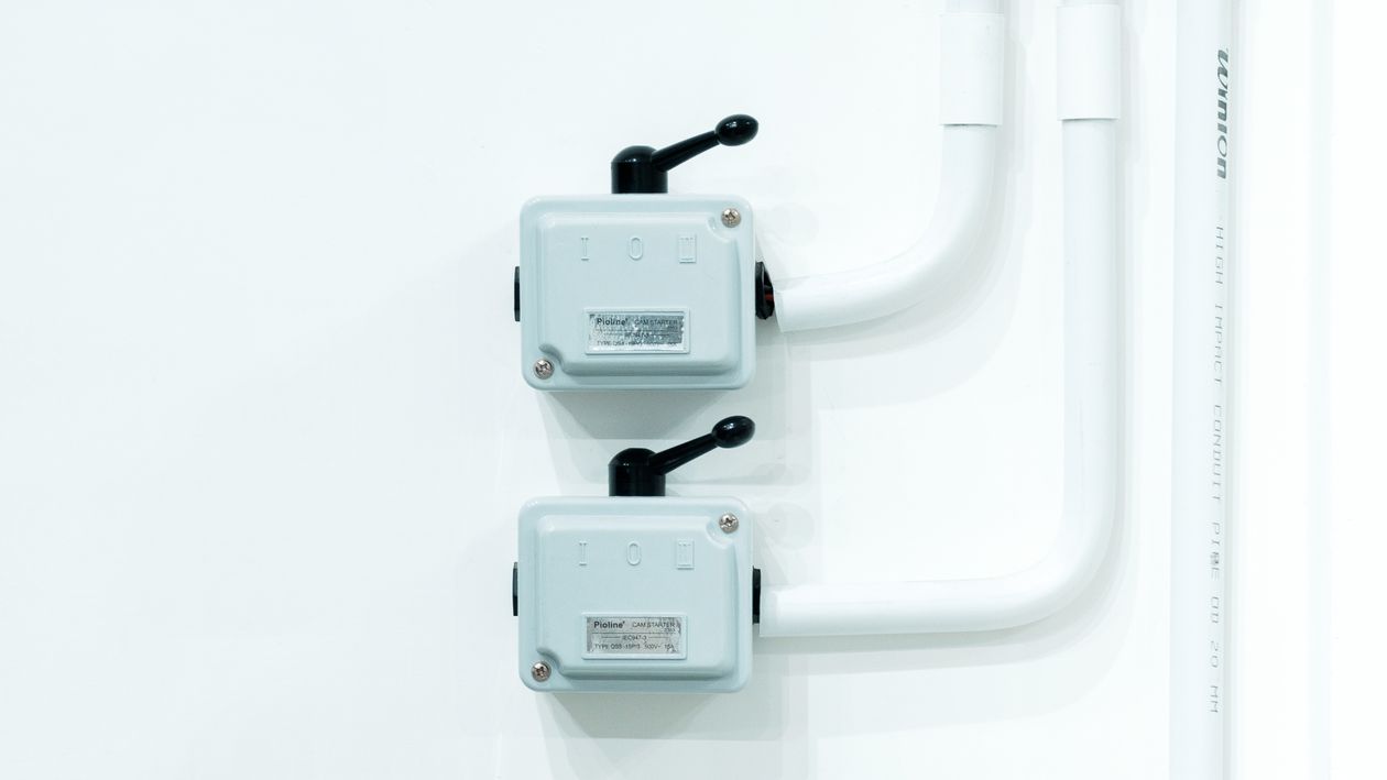 Electrical switches mounted on a white wall with visible conduit