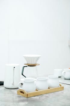 A clean and elegant setup for coffee brewing with white porcelain cups and a dripper.