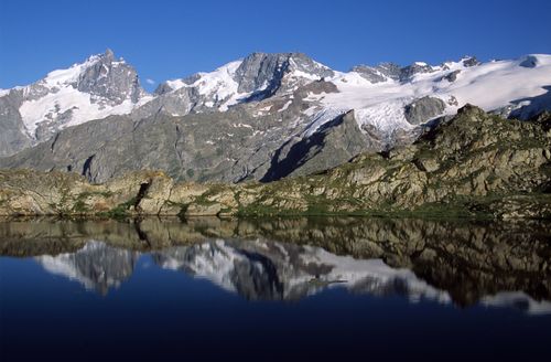 Free Snow-capped mountains reflected in a serene lake in La Grave, France. Stock Photo