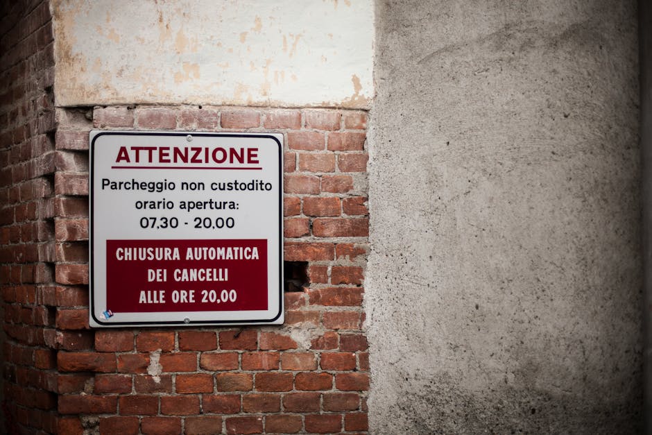 Italian parking warning sign on brick wall. Indicates gate closure times.