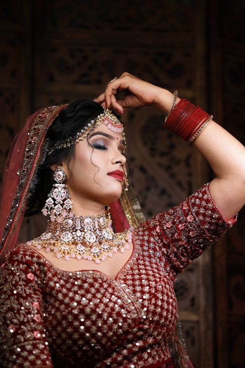 Free A stunning South Asian bride wearing a traditional lehenga and ornate jewelry, posing gracefully indoors. Stock Photo