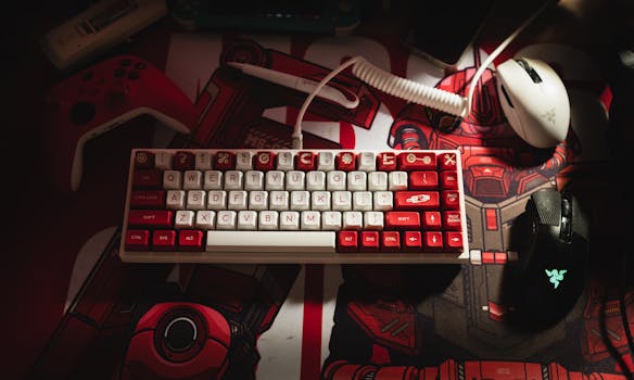Close-up of a mechanical keyboard with red and white keys alongside gaming peripherals on a themed desk mat.
