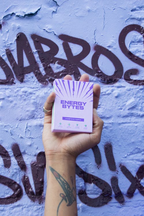 Man holding energy gummies in front of a wall