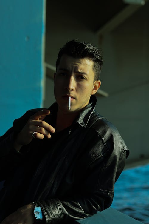 Man in a Black Leather Jacket Smoking a Cigarette
