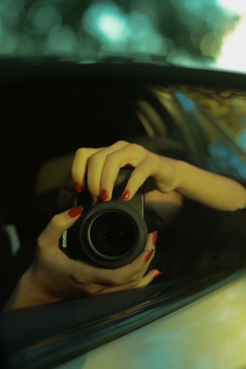Free Close-up of hands holding a camera in a reflective surface. Stock Photo