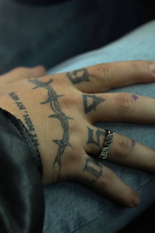 Free Detailed close-up of a tattooed hand wearing a silver ring on a denim background. Stock Photo
