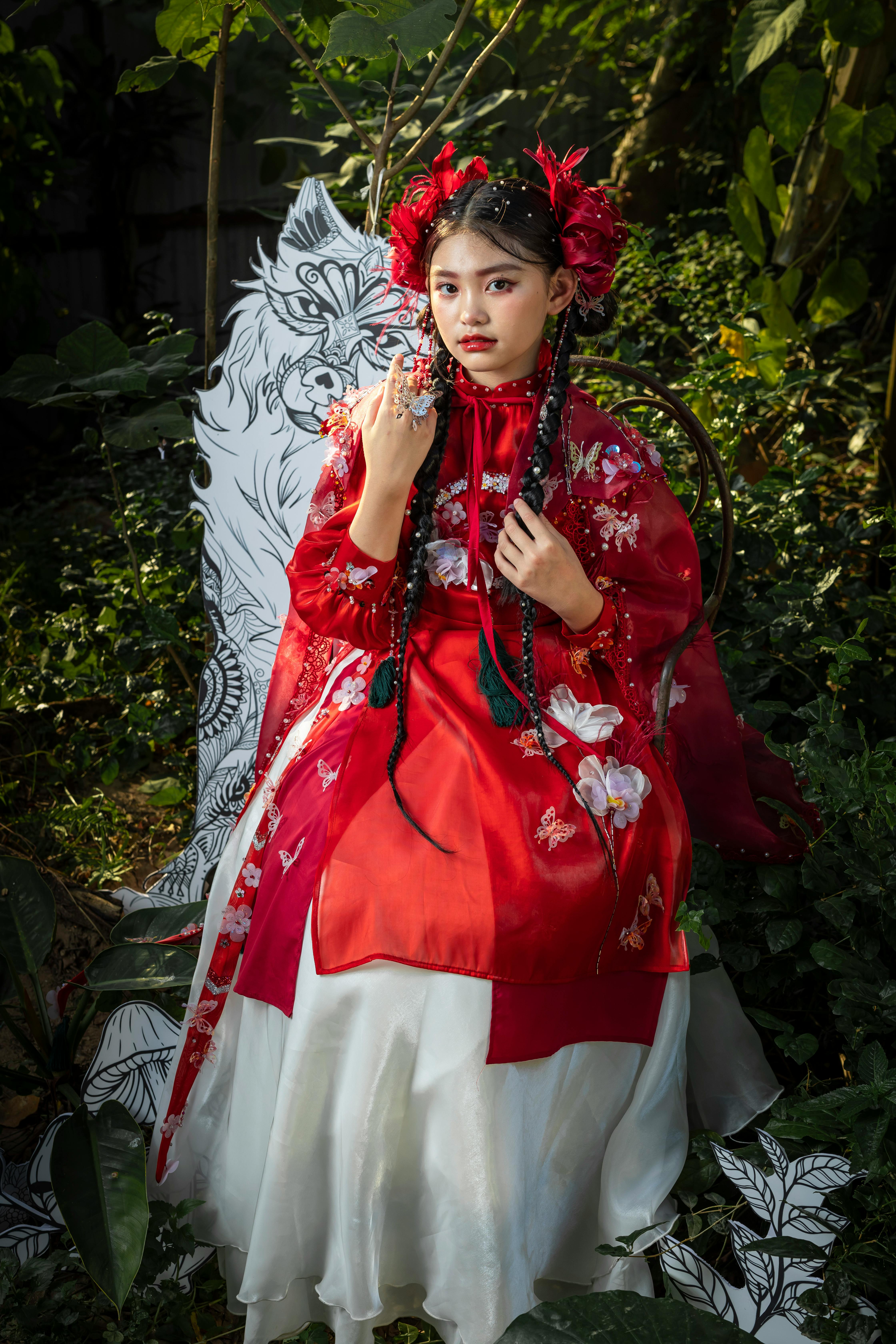 woman in red and white dress standing beside green plant