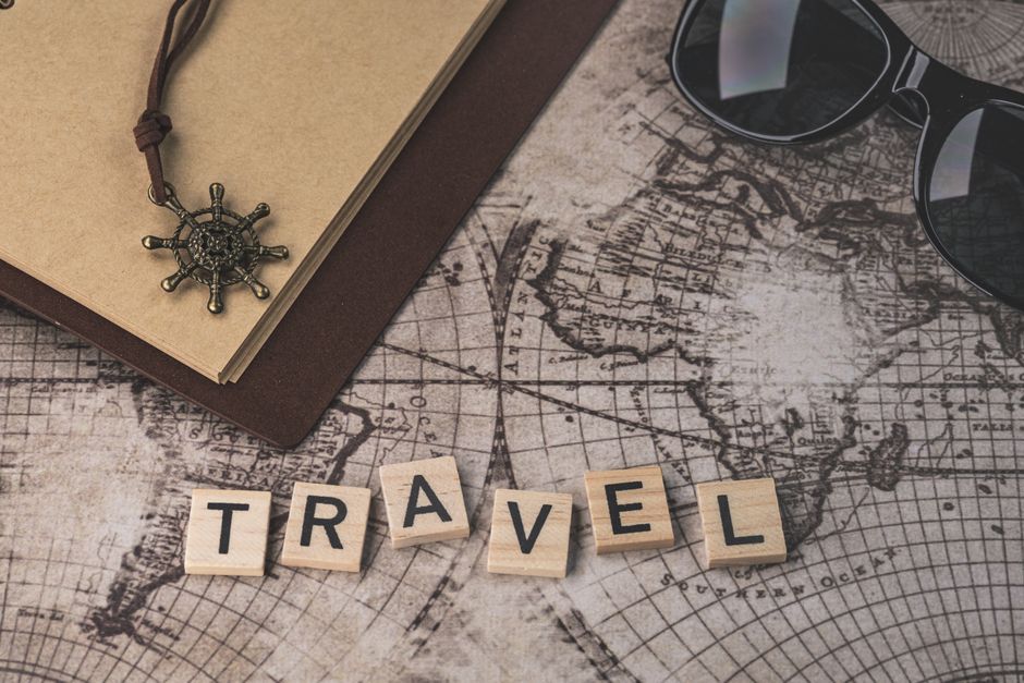 Voyager Malin en 2026 : Les Meilleurs Promos et Bons Plans pour Partir à Petit Prix 2 Close-up of travel items including map, helm pendant, notebook, and sunglasses.