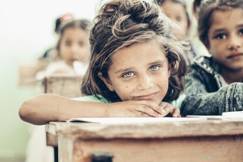 Free Portrait of a young girl with beautiful eyes smiling at a desk in Syria. Stock Photo