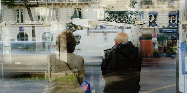 Elderly Woman And Man Sitting On Bus Stop