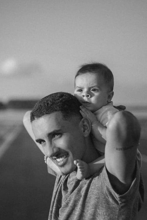 Grayscale Photo of a Man Carrying a Baby