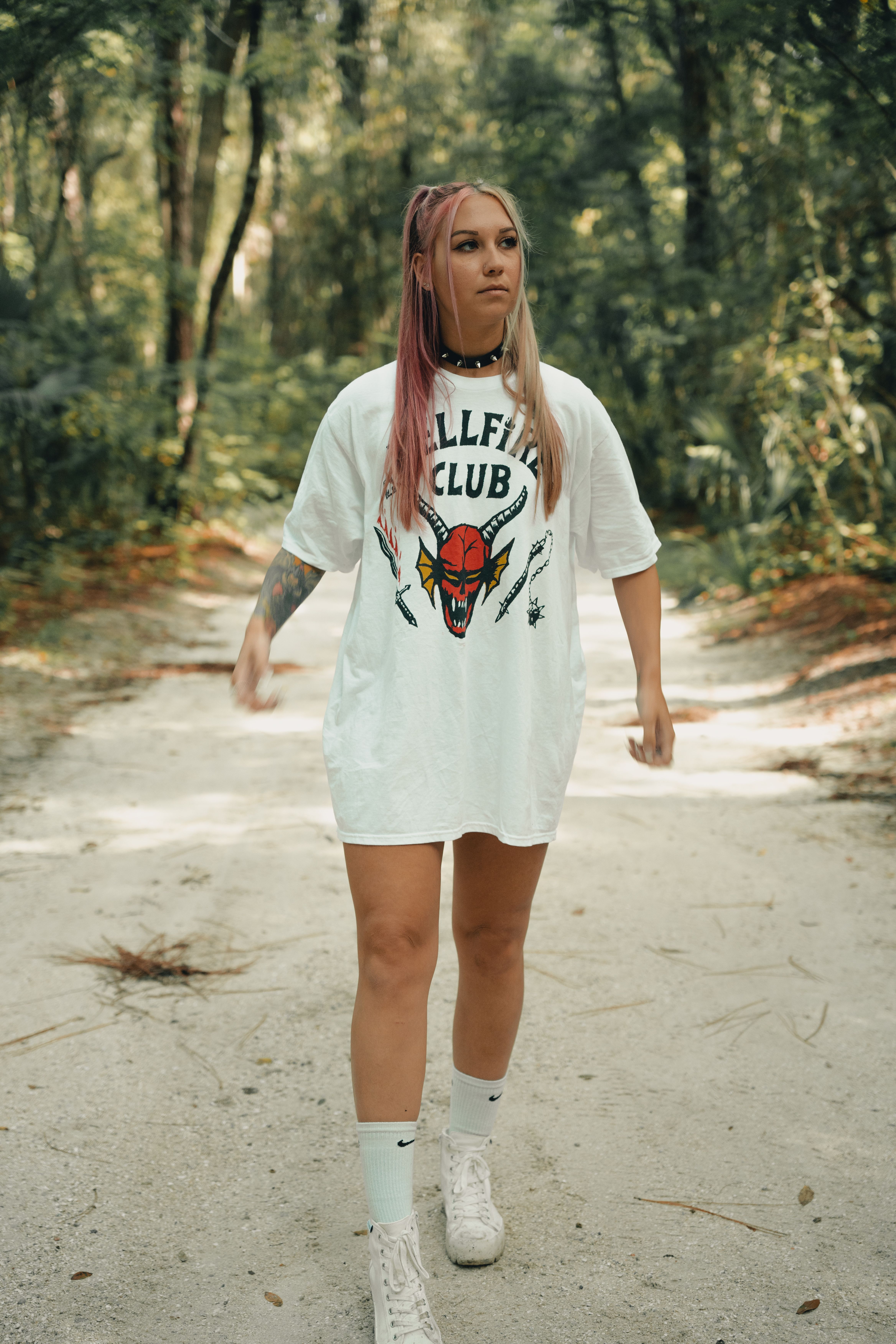 Casual stroll in nature, woman wearing graphic tee in lush forest.