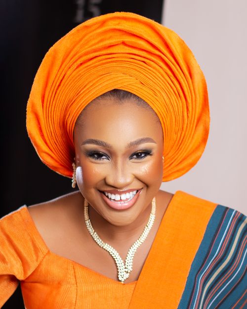 Free Beautiful African woman smiling in vibrant orange traditional attire with headwrap. Stock Photo