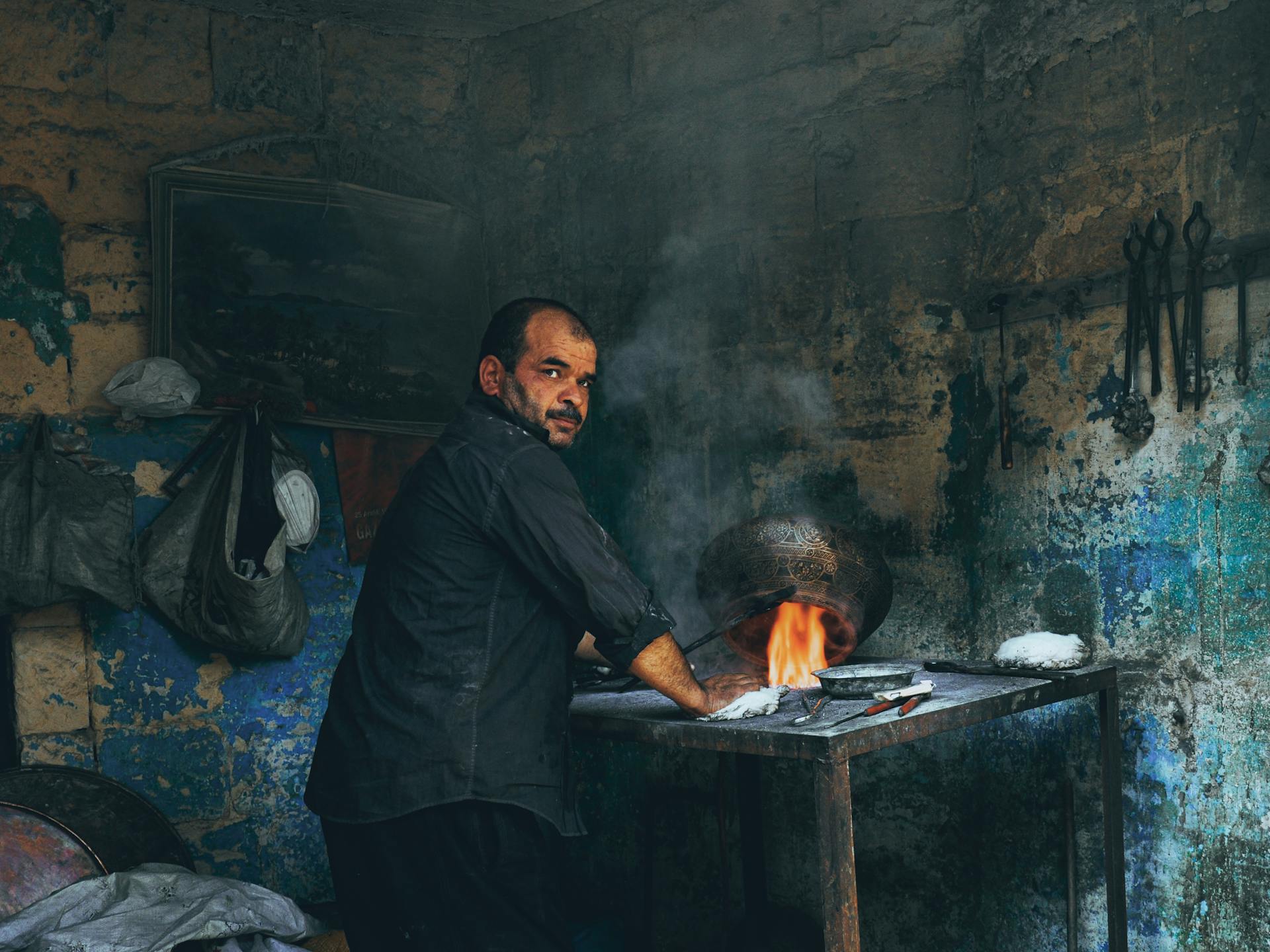 A dedicated blacksmith working with fire and metal in a rustic workshop setting.