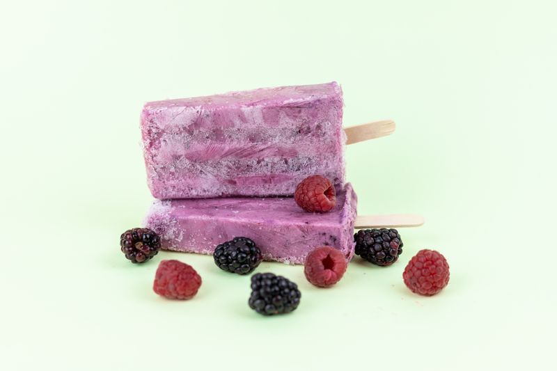 Two deep purple ice pops studded with raspberries and blackberries