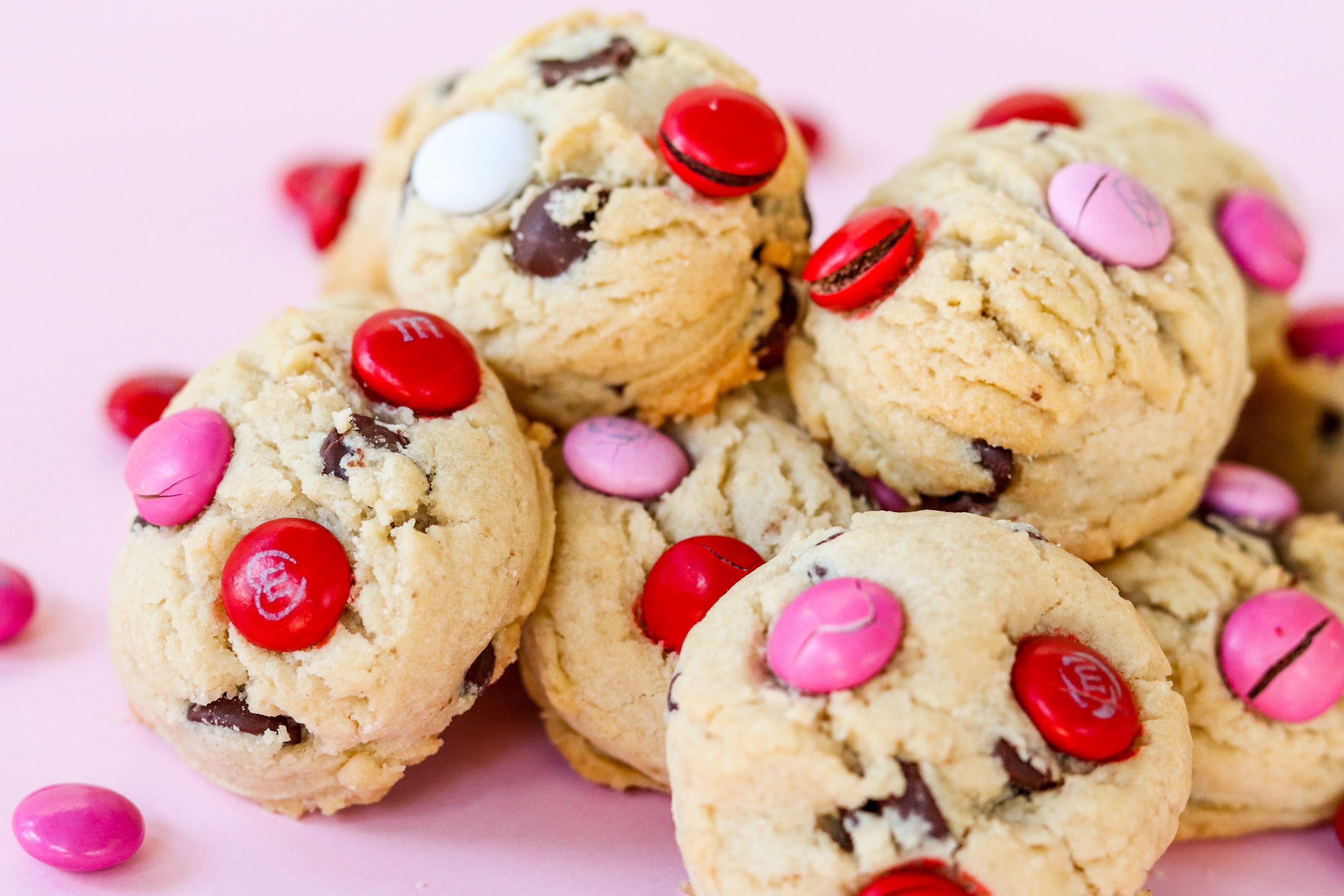 Close-up of colorful M&M cookies on a pink backdrop, perfect for sweet treats and dessert imagery.
