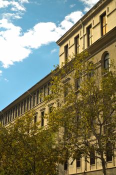 Charming view of neoclassical building facade with trees under blue sky.