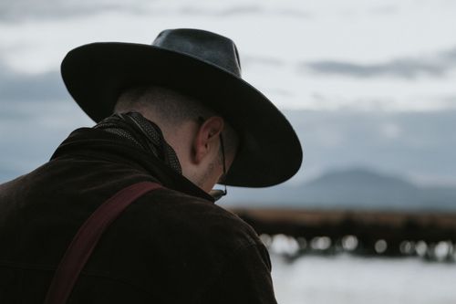 Free A man in a black hat gazing into a serene landscape with mountains. Stock Photo