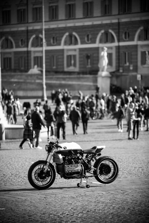 Grayscale Photo of Sports Bike Parked Near People