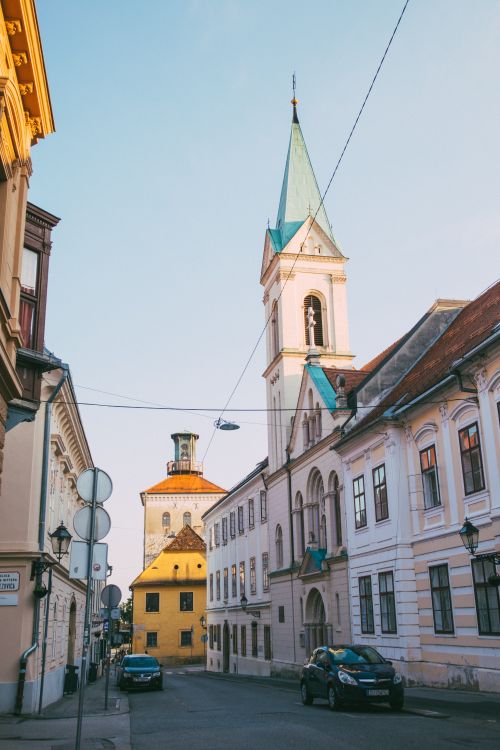 Free Charming European street view with historic church and townhouses under a clear sky. Stock Photo