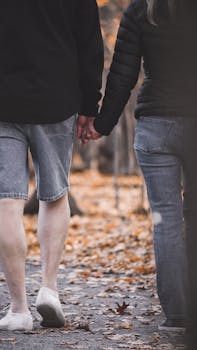 Couple walking hand in hand on a fall day, captured from behind.