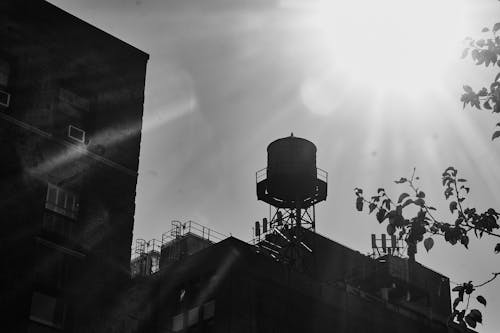 Grayscale Photo of a Water Tank on top of a Concrete Building