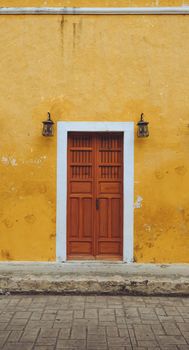 Capture of a wooden door on a vibrant yellow wall with vintage lanterns.